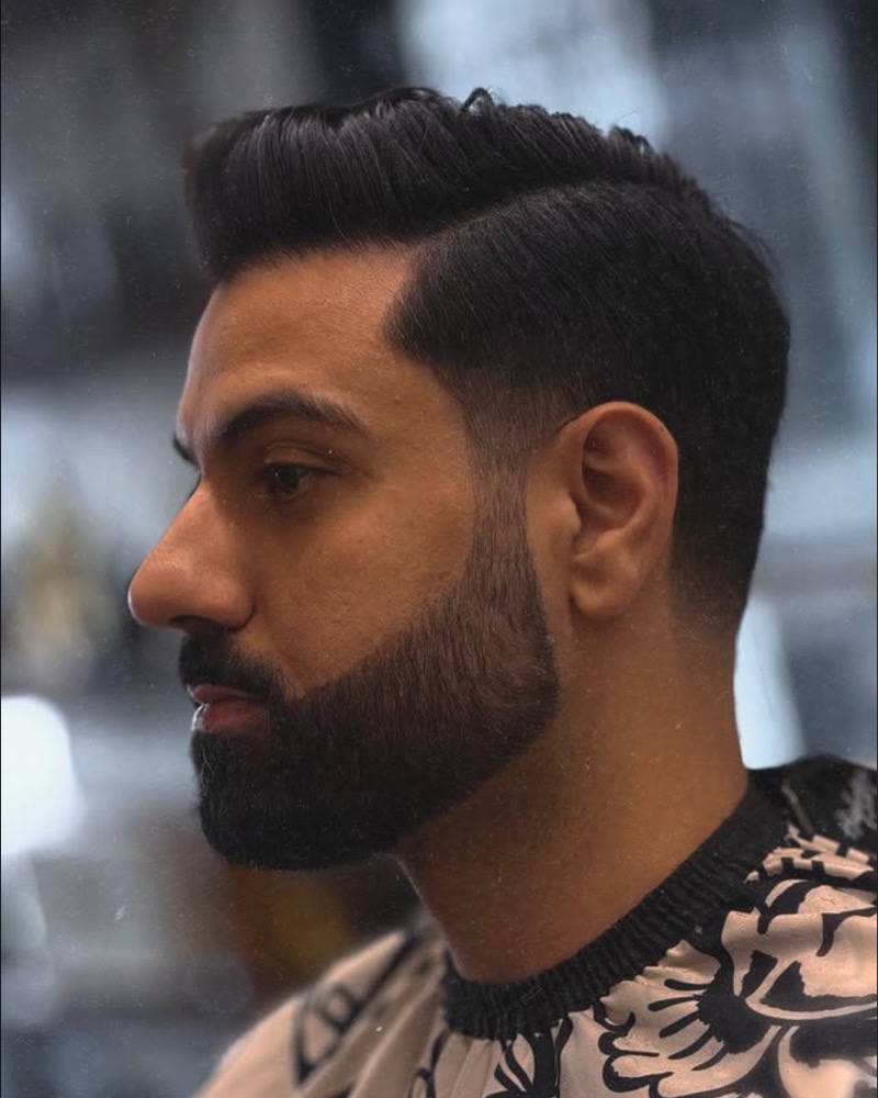 Full beard trim with a sharp razor line-up and side part, side profile
